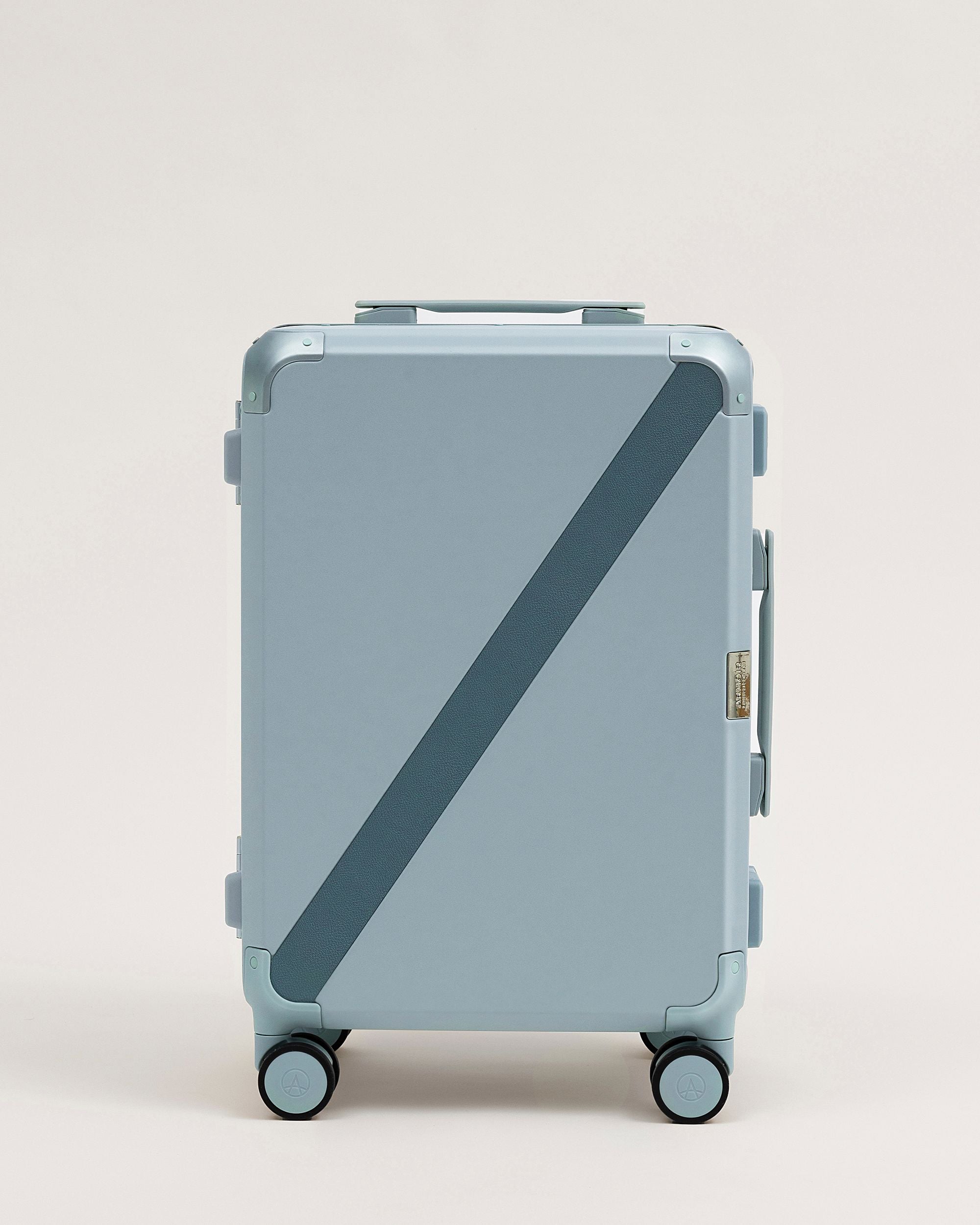 Light blue suitcase with a diagonal black stripe on a light beige background